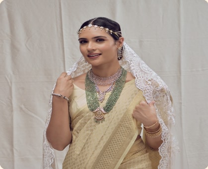 Woman in a cream saree wearing layered bead necklaces